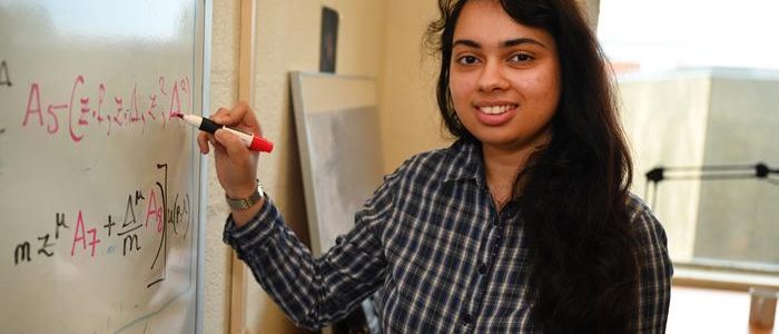 Head shot of Shohini in front of her white board with physics equations in her office at BNL